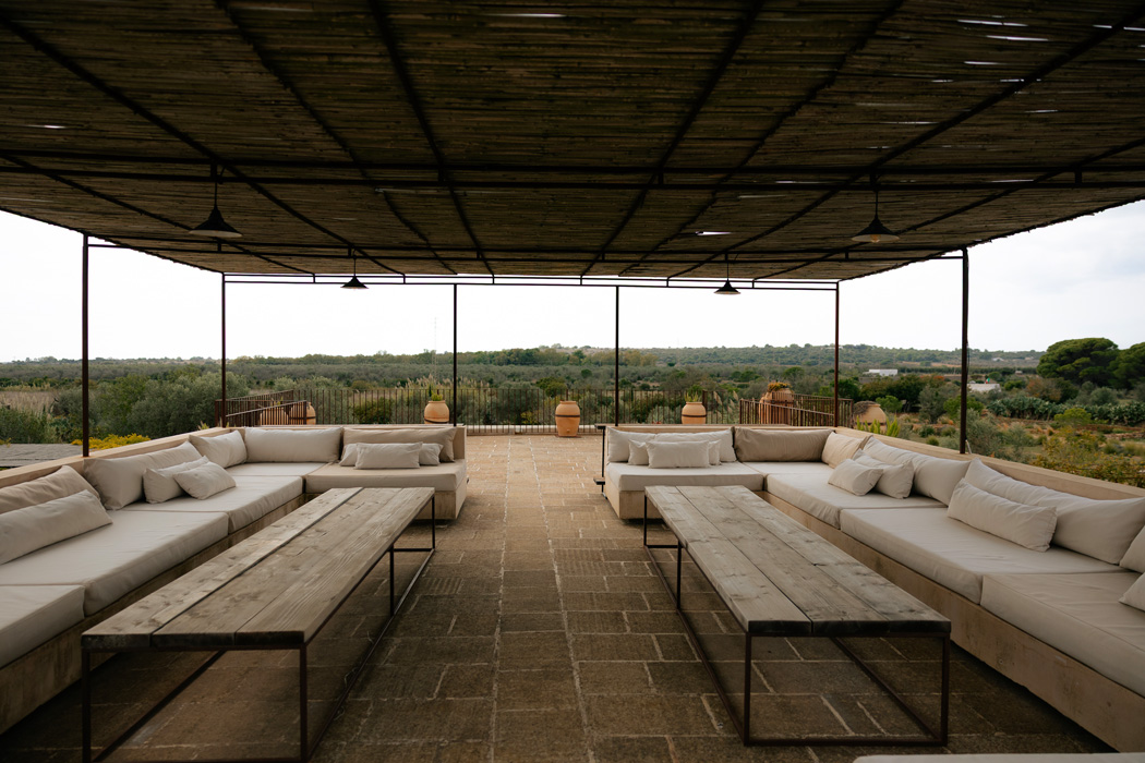 Ampia terrazza coperta con divani in stile mediterraneo e vista sulla campagna pugliese.