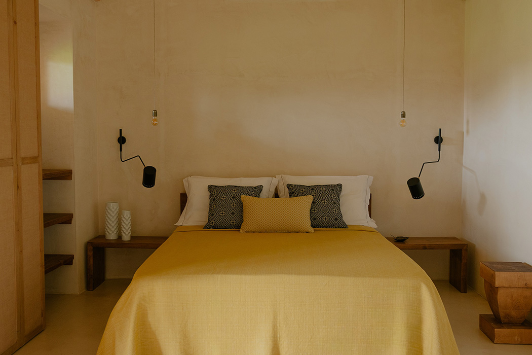 Camera Junior Suite con letto matrimoniale, arredi minimal e illuminazione calda.