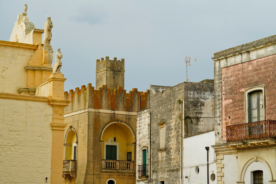 Edifici storici in pietra nel centro di un borgo salentino con dettagli architettonici tradizionali.