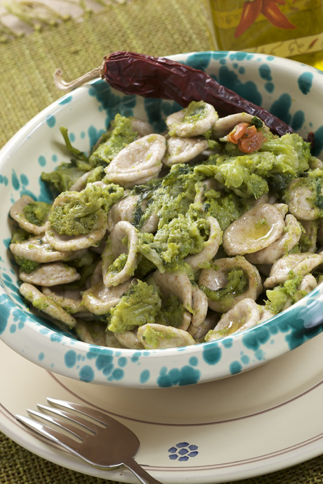 Piatto di orecchiette condite con cime di rapa e peperoncino servito in ceramica decorata.