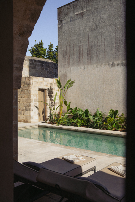 Vista sulla piscina di Le Cinquestanze con lettini relax e vegetazione mediterranea.