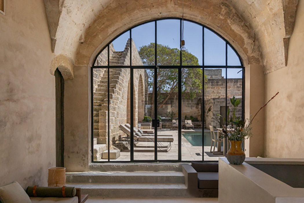 Interno con grande vetrata ad arco affacciata sulla piscina.
