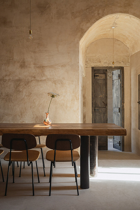 Sala da pranzo con tavolo in legno e volte in pietra.
