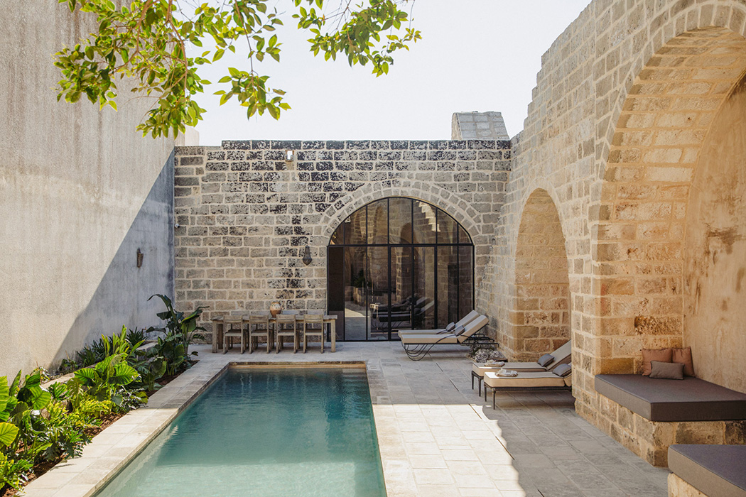 Corte interna con piscina, archi in pietra e area relax.