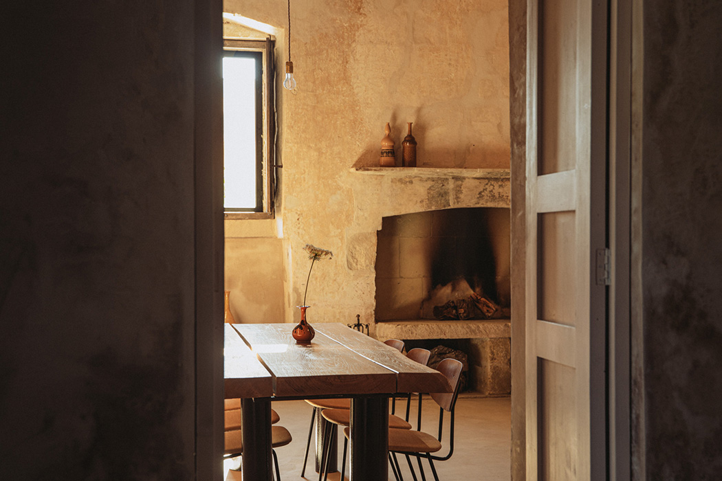 Sala da pranzo con camino in pietra, tavolo in legno e luce naturale.